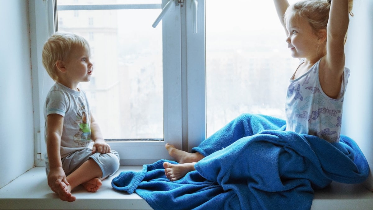two children sitting near the window and communicate with each other